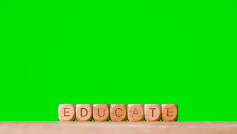 Education-Concept-With-Wooden-Letter-Cubes-Or-Dice-Spelling-Educate-Against-Green-Screen-Background